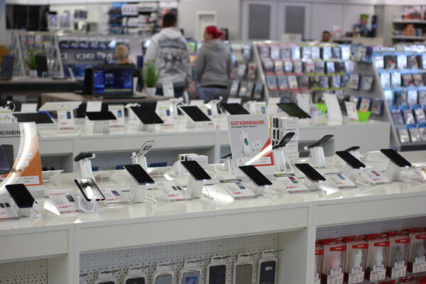 Smartphones mit Diebstahlsicherung auf Präsentationstischen im Elektronikmarkt